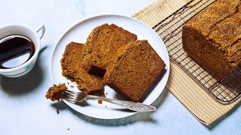 Slices of sweet potato bread on plate with fork with coffee and a whole loaf on the side