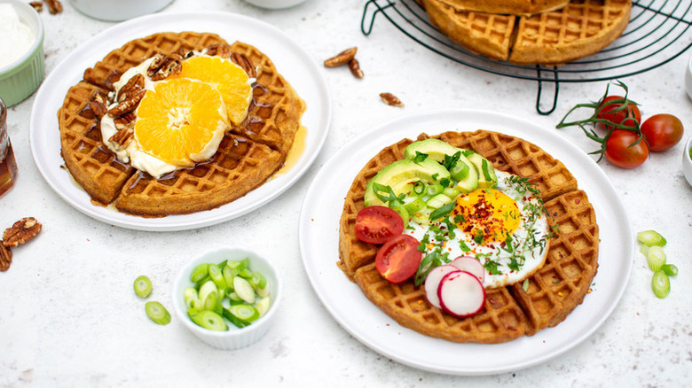 Two plates of sweet potato waffles with various sweet and savory toppings