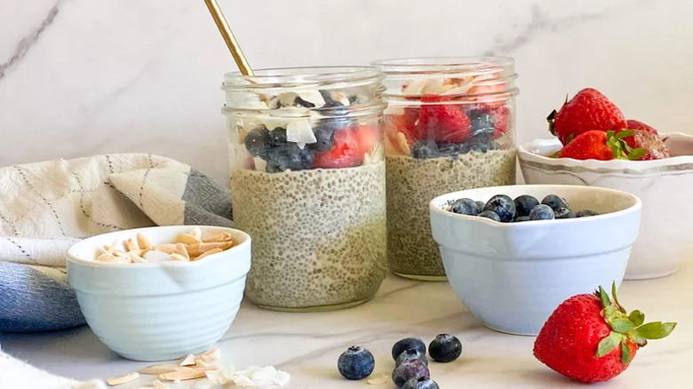 Classic Chia Pudding in glass jars with bowls of fruit and nuts