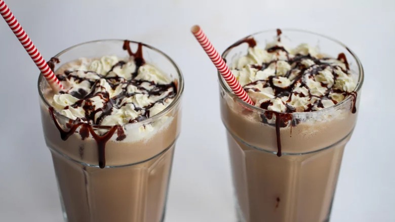 Two chocolate milkshakes with red striped straws
