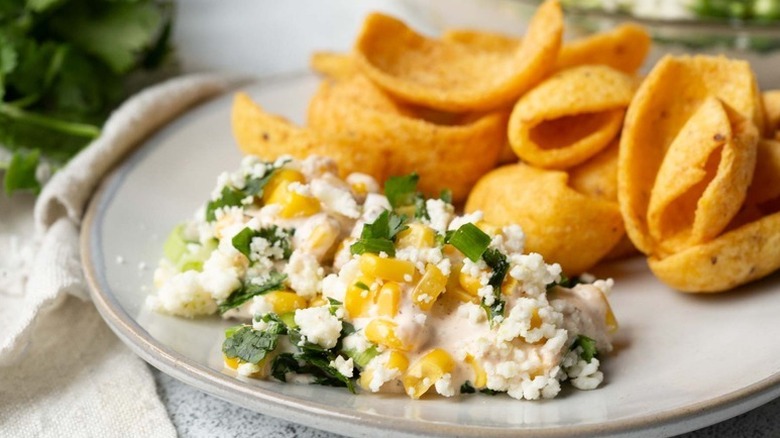 Elote-style corn dip served onto plate with Fritos scoops