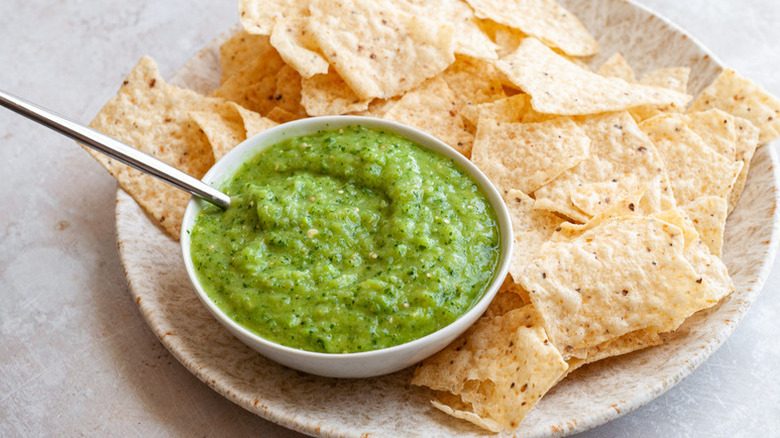 Bowl of salsa verde on plate with tortilla chips