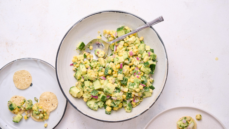Bowl of cucumber, corn and avocado salsa with spoon