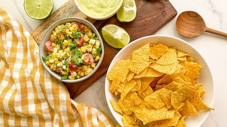 Bowl of elote-style corn dip next to bowl of tortilla chips