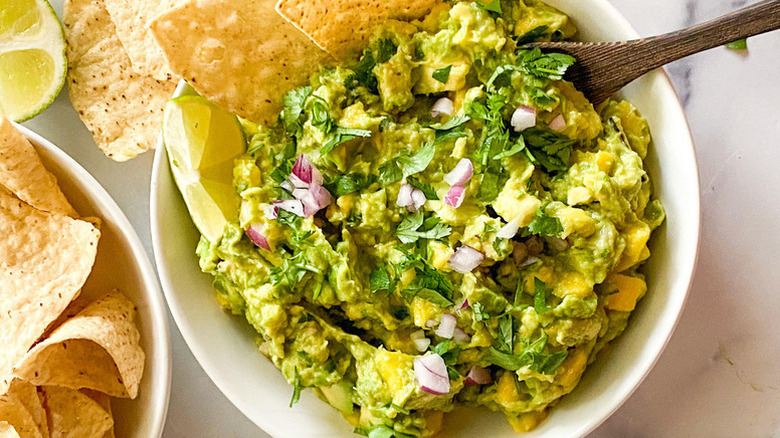 Mango guacamole in bowl with lime wedge and tortilla chips