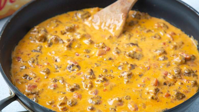 Rotel queso with chorizo in skillet with wooden spoon