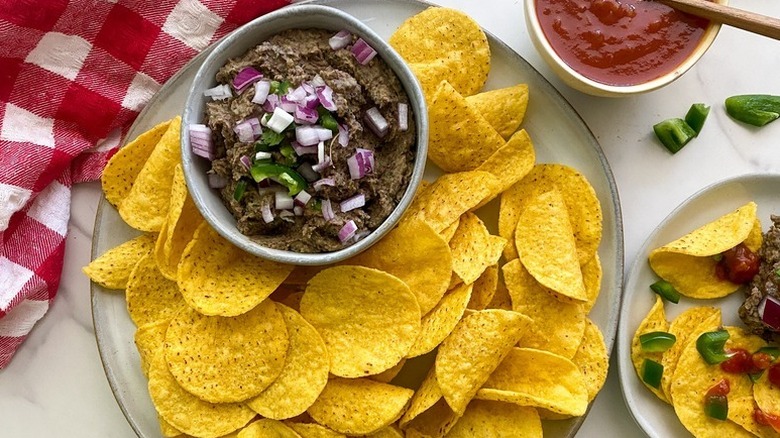 Bowl of black bean dip on plate with tortilla chips