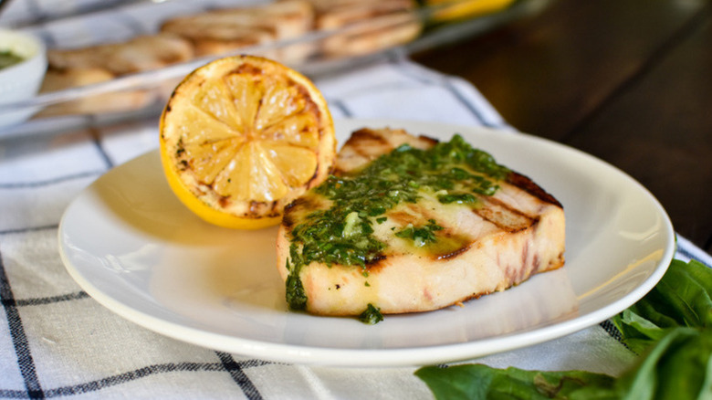 Grilled swordfish on plate with herb vinaigrette and charred lemon half