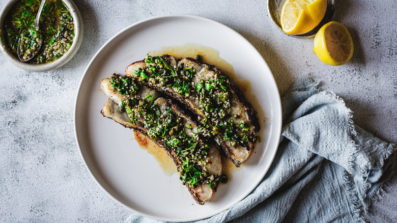Grilled sea bass on plate, topped with herby garlic sauce
