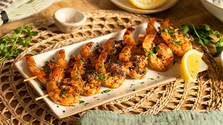 Grilled shrimp skewers on plate with lemon wedge