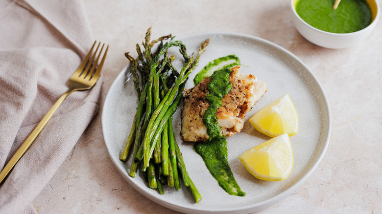 Grilled cod on plate with asparagus and lemon wedges