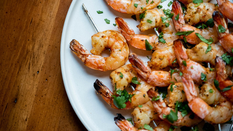 Grilled shrimp skewers on plate with fresh herb garnish