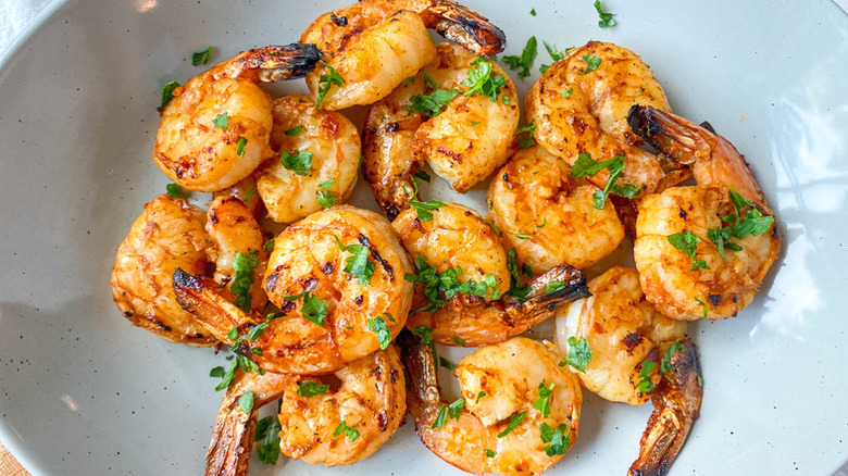 Spicy grilled shrimp in bowl, topped with fresh parsley
