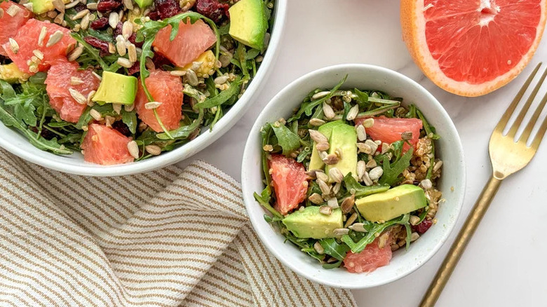 Grapefruit and Arugula Salad with Quinoa in white bowl with gold fork