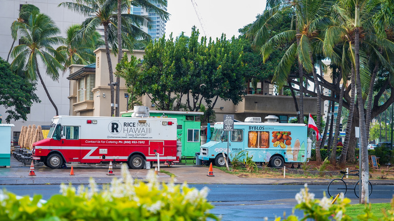 Food trucks gathered beneath palm trees in Hawaii