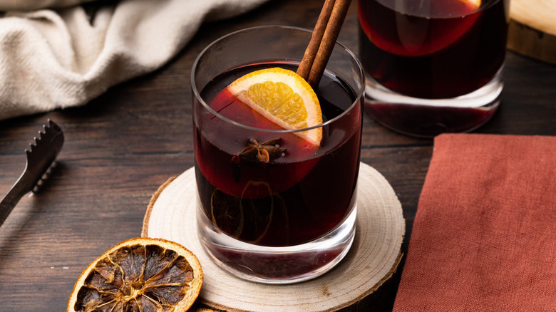 Glass of gluhwein garnished with orange slice and cinnamon sticks