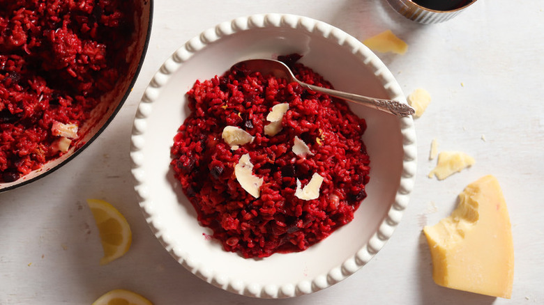 Beet risotto in white bowl, garnished with shaved Parmesan
