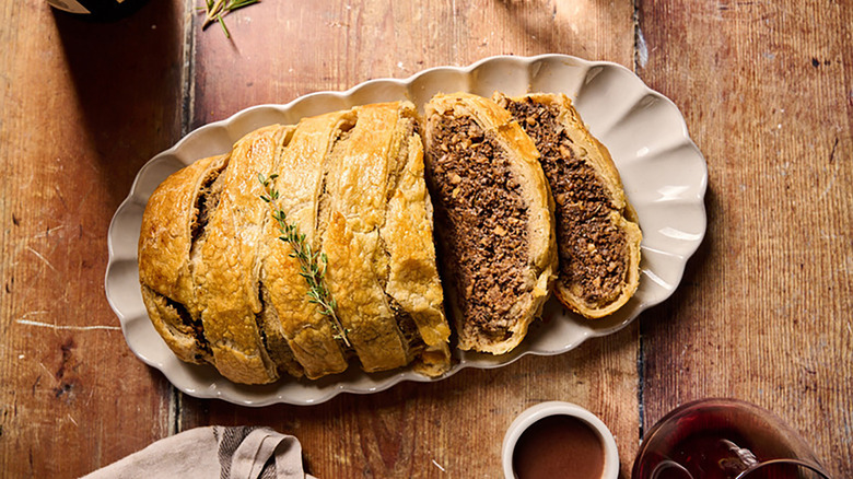 Sliced vegetarian porcini wellington on white scalloped plate