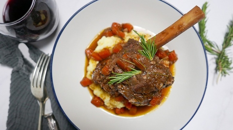 Braised lamb shanks in bowl with mashed potatoes and carrots
