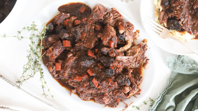 Chuck pot roast with figs and carrots, served in white bowl