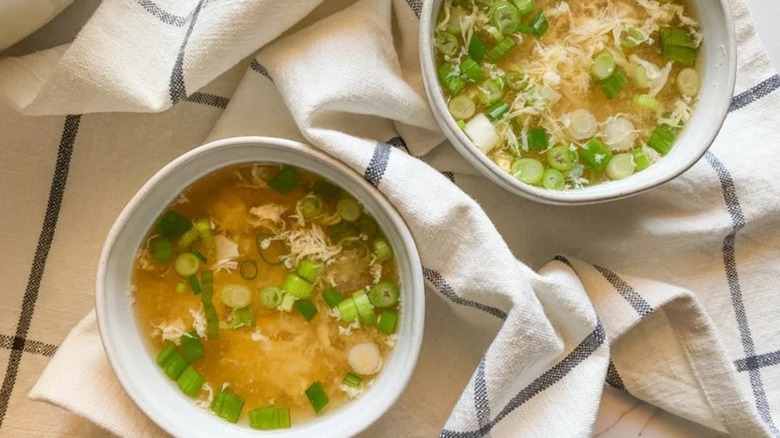 Two bowls of egg drop soup topped with green onions