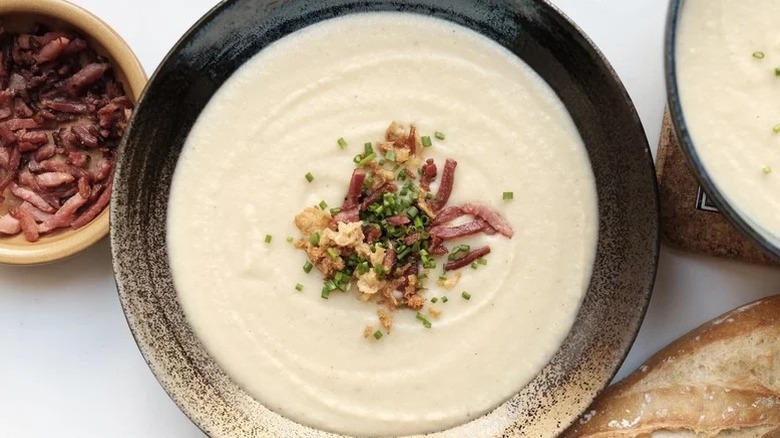 Bowl of cauliflower potato soup topped with bacon bits, chives, and fried onions