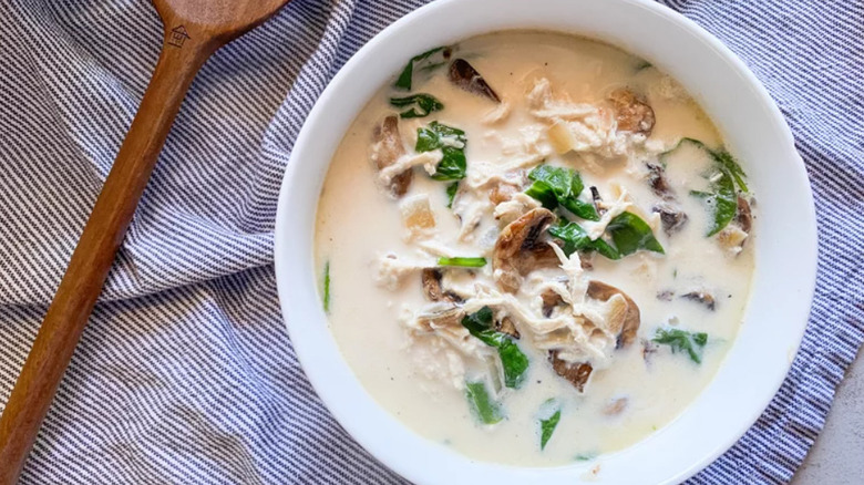 Chicken spinach soup with wooden serving spoon on cloth napkin