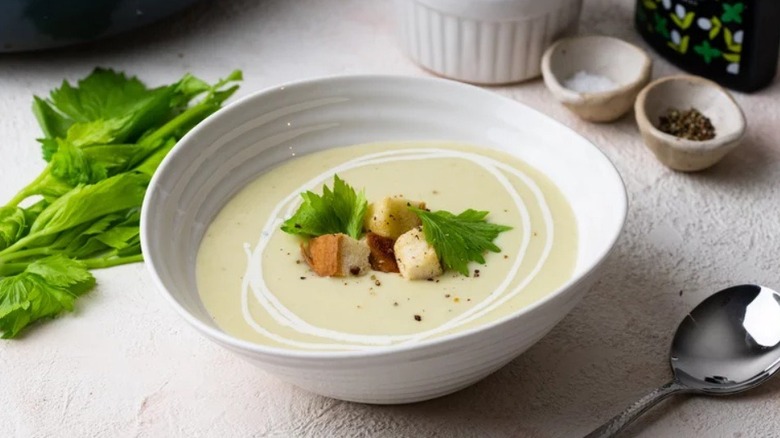 Cream of celery soup in bowl topped with croutons and celery leaves