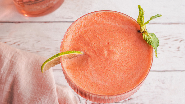 Frozen watermelon cocktail in coupe glass, garnished with lime slice and mint sprig