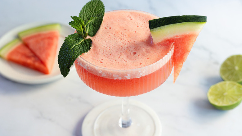Watermelon margarita in coupe glass, garnished with watermelon wedge and mint sprig