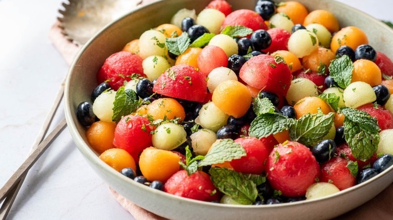Bowl of fruit salad with melon balls, blueberries and mint