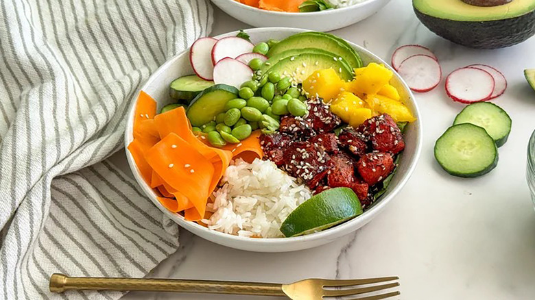 Poke bowl with marinated watermelon, sliced avocado, carrot ribbons, diced mango, and edamame