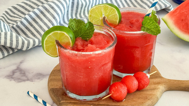Watermelon slushies in glasses, garnished with lime slices and fresh mint