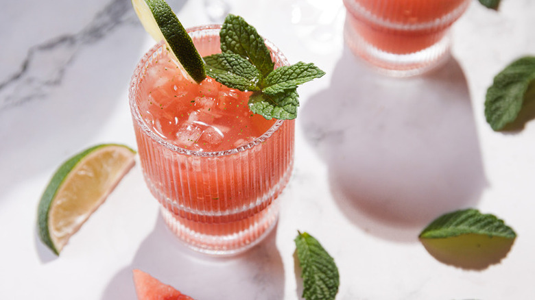 Watermelon mocktail in glass, garnished with mint sprig and lime slice
