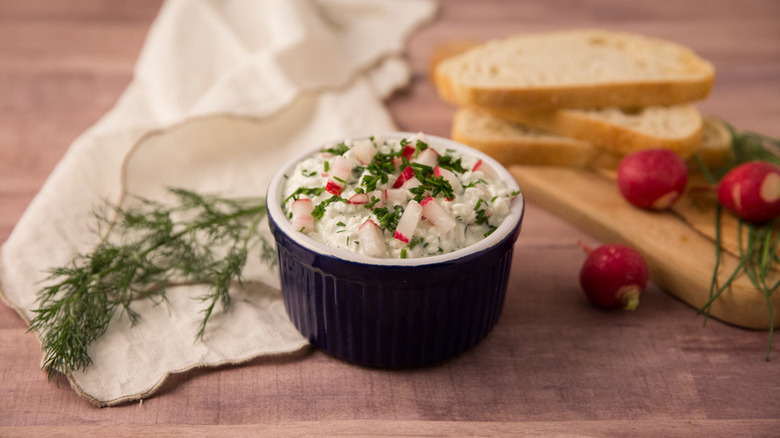 Creamy gzik dip in black ramekin, garnished with radish and chopped green herbs