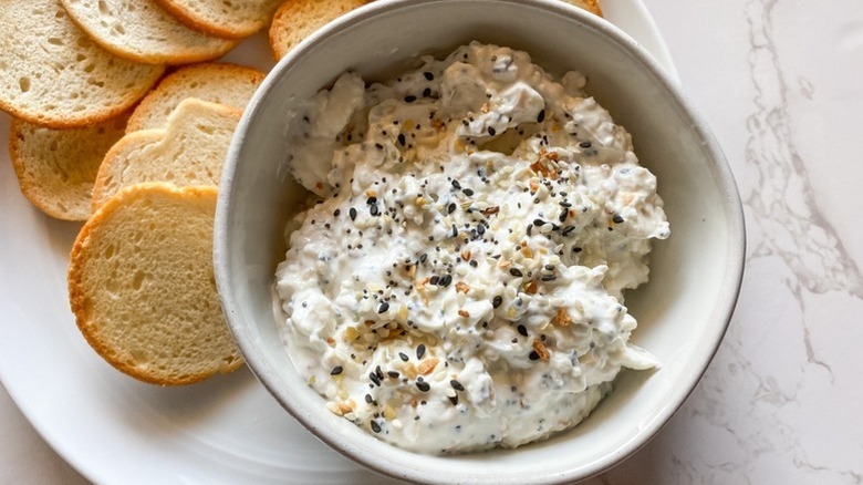 Creamy everything bagel dip in bowl, garnished with everything bagel seasoning