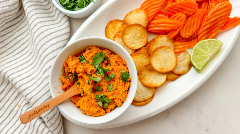 Bowl of sweet potato dip on platter with crackers