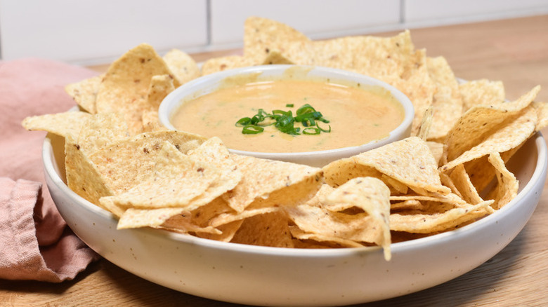 Bowl of white queso dip surrounded by tortilla chips