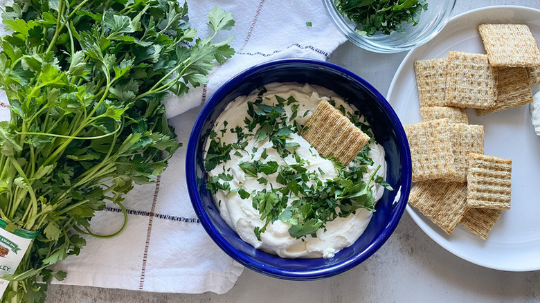 Whipped feta dip in blue bowl, garnished with fresh parsley and served with crackers