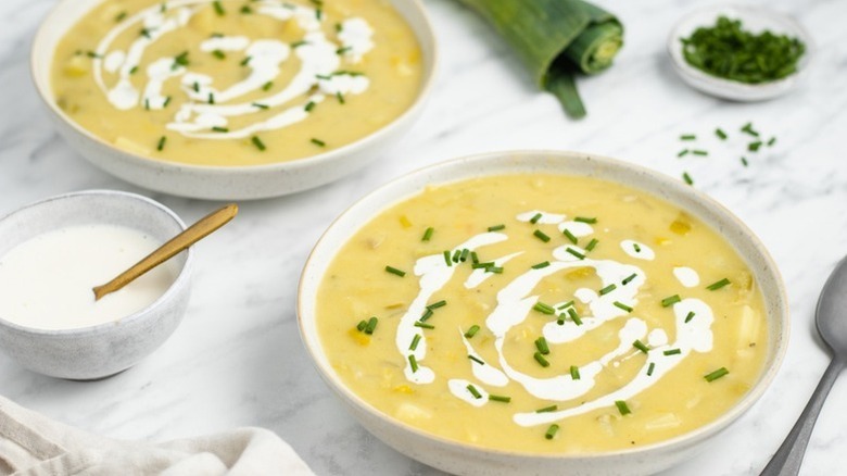Two bowls of potato leek soup, garnished with cream and chives