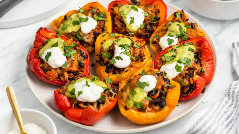 Plate of stuffed bell peppers, topped with guacamole, sour cream, and cilantro
