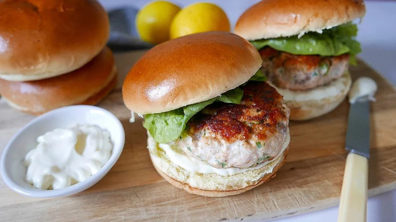 Salmon Burgers with sauce on wooden cutting board
