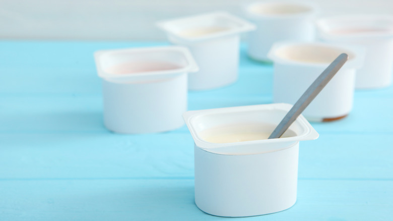 Open containers of yogurt on blue table 