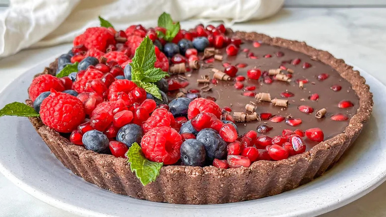 Vegan, Gluten-Free Chocolate Pomegranate Tart topped with fruit on white plate