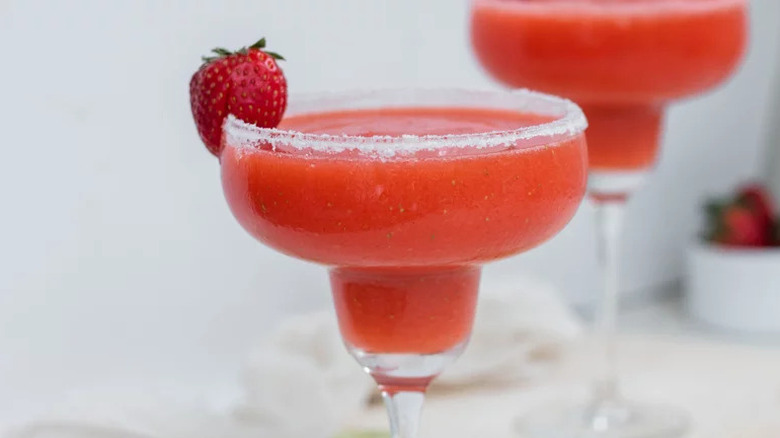 Frozen Strawberry Margarita in margarita glasses with strawberry garnish