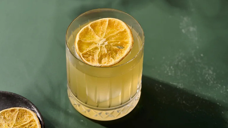Orange-Centric Golden Margarita with dried orange slice on green surface