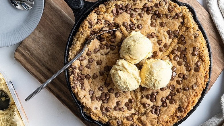 Skillet chocolate chip cookie topped with scoops of vanilla ice cream