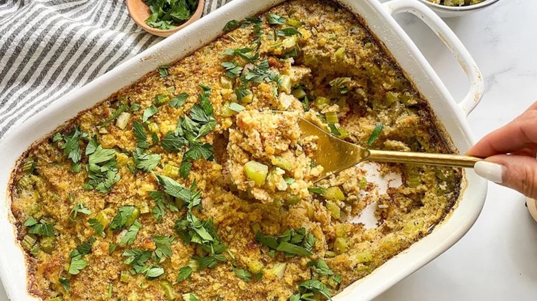 Spooning cornbread dressing from casserole dish