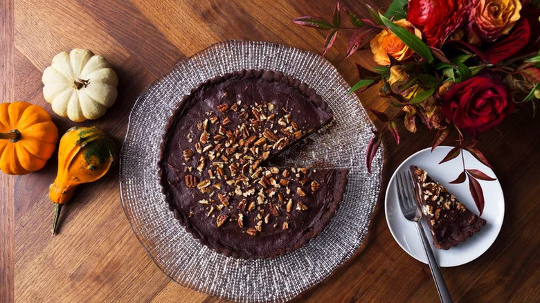 Mexican Chocolate-Pecan Tart on wooden table with flowers and pumpkins
