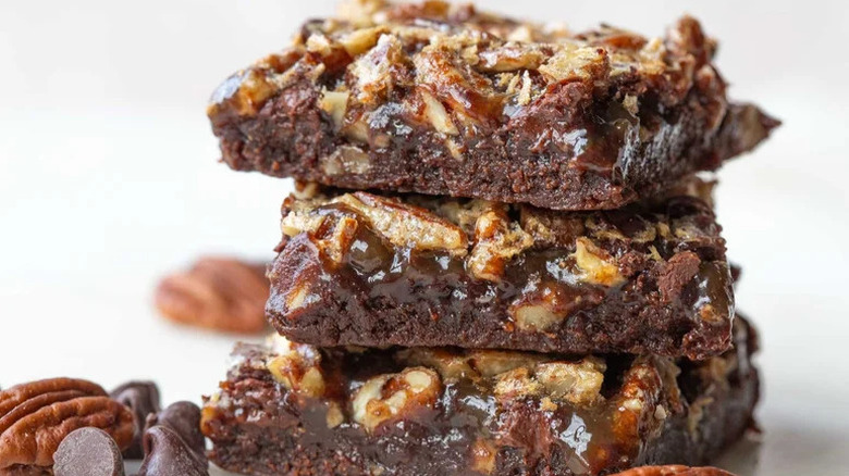 Fudgy Chocolate Chip Pecan Pie Brownies stacked on top of each other